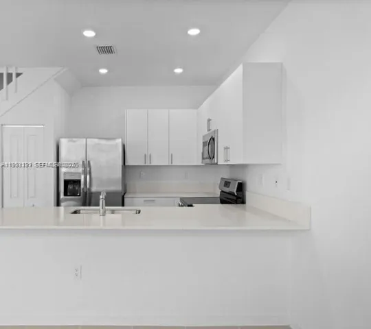 a kitchen with stainless steel appliances sink refrigerator and microwave