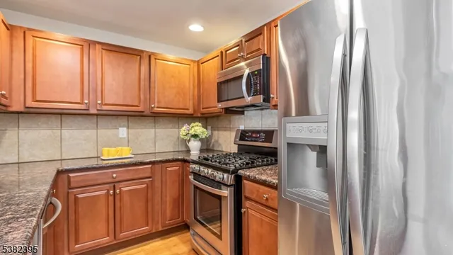 a kitchen with stainless steel appliances granite countertop a refrigerator a stove a sink and dishwasher