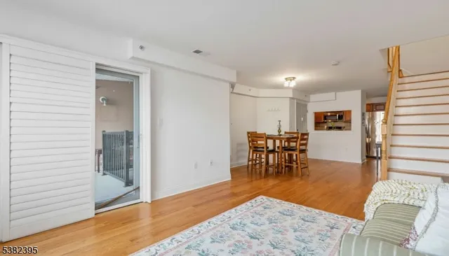 a living room with furniture and kitchen view with wooden floor