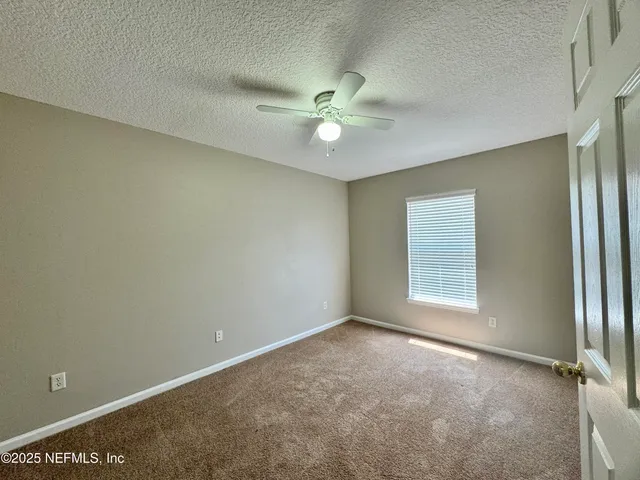 an empty room with windows and fan