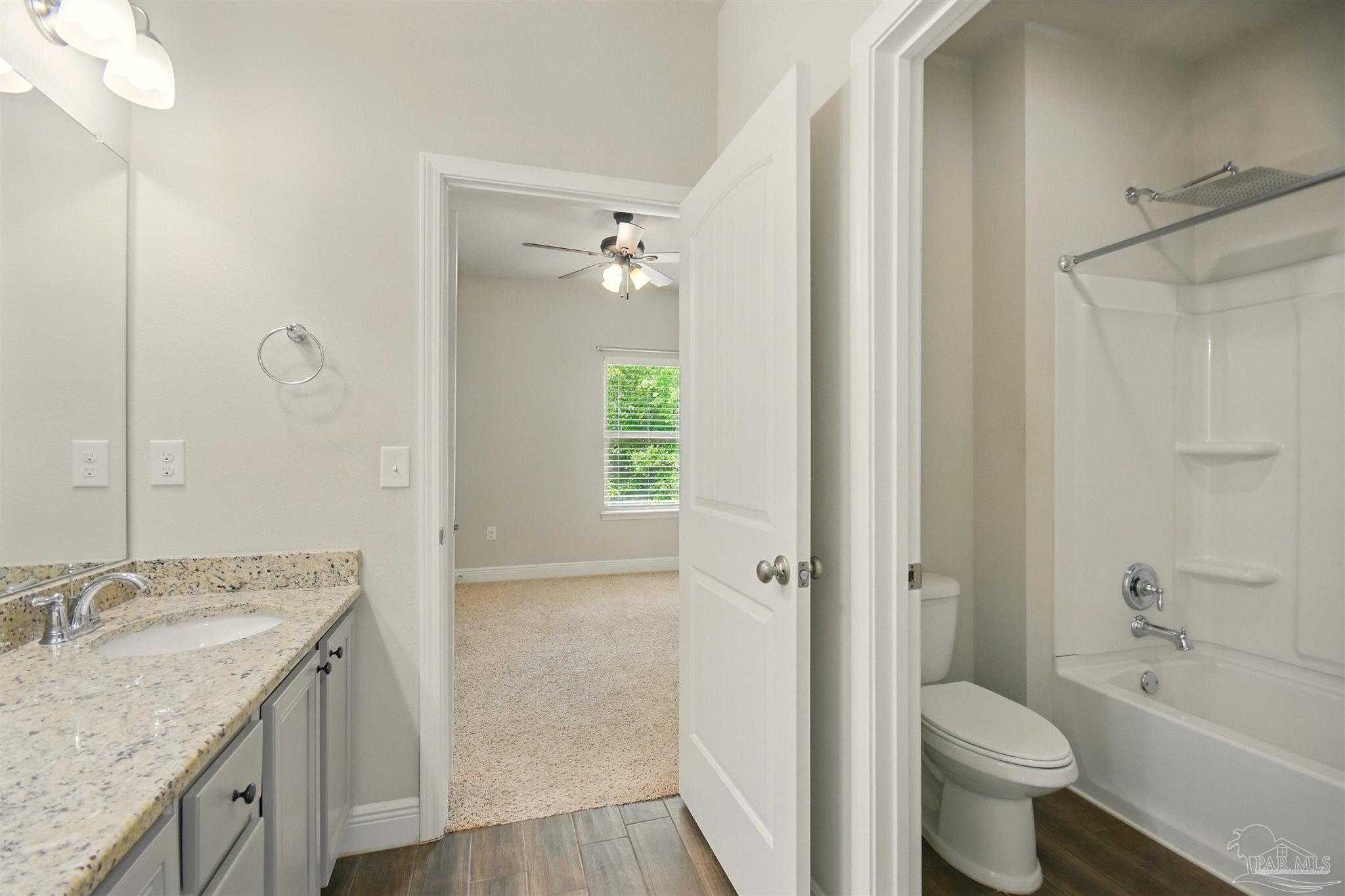 2701 Tulip Hill Road Pace, FL 32571 - Photo 21 of 42 a bathroom with a granite countertop sink a toilet and shower