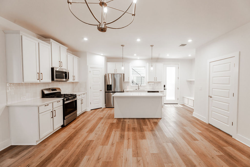 Gleaming hardwood floors and a spacious central island anchor this open culinary space.