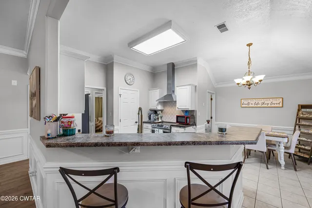 a kitchen with stainless steel appliances granite countertop a kitchen island and chairs in it