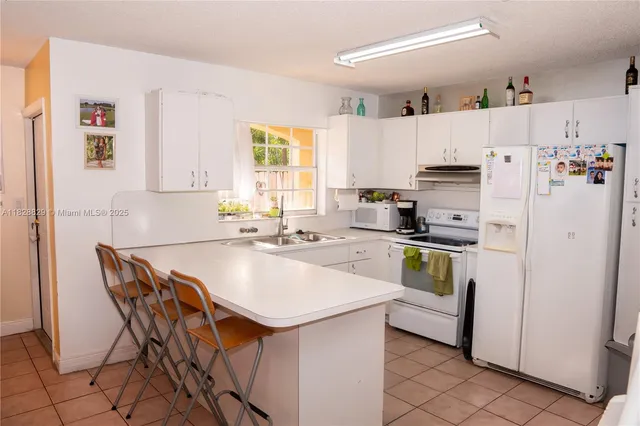 a kitchen with a sink a stove a refrigerator and white cabinets