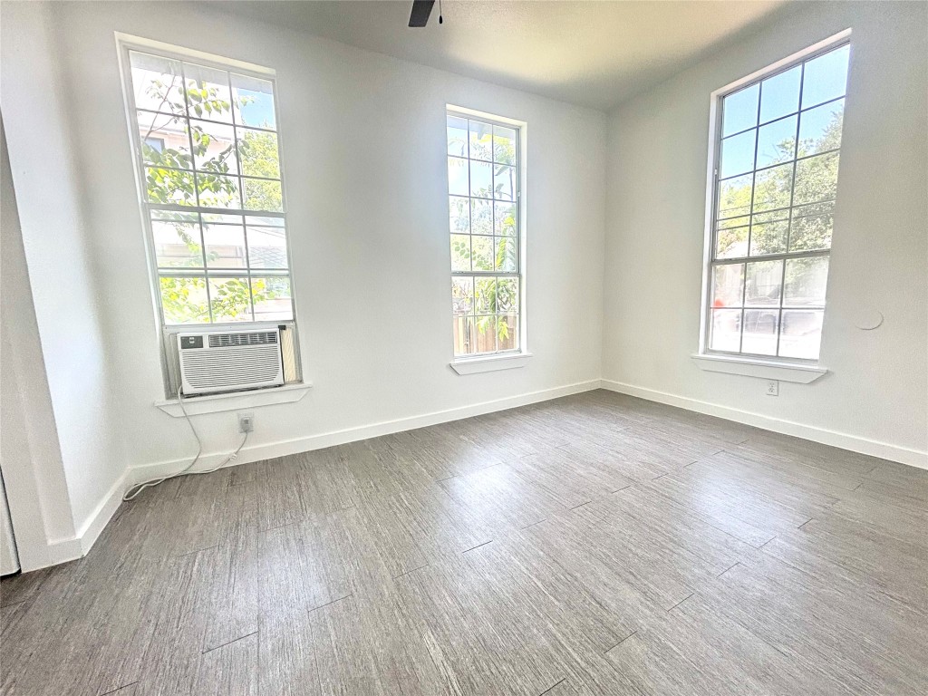 2410 East 12th Street Austin, TX 78702 - Photo 8 of 17 Unfurnished room featuring plenty of natural light, dark wood-type flooring, ceiling fan, and cooling unit