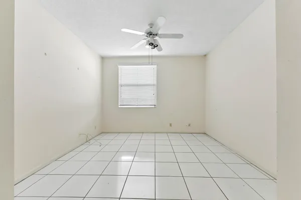 an empty room with a ceiling fan and window