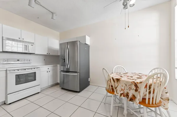 a kitchen with stainless steel appliances granite countertop a stove top oven a sink a dining table and chairs