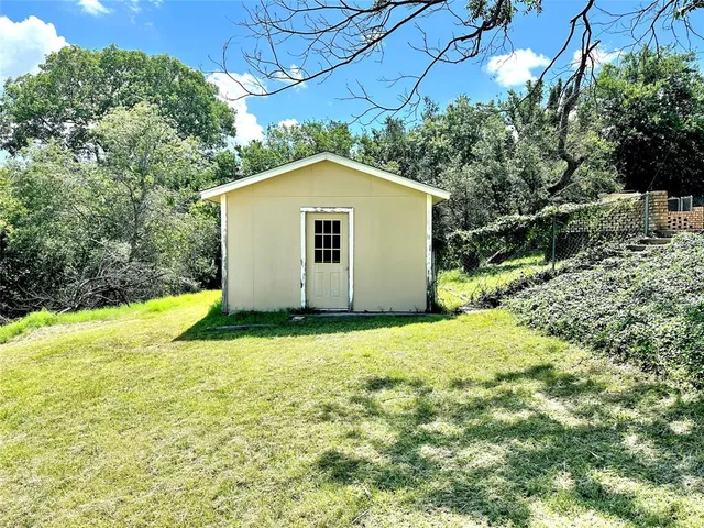 a view of backyard of house with large tree and wooden fence