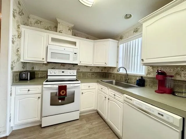 a kitchen with white cabinets and white appliances