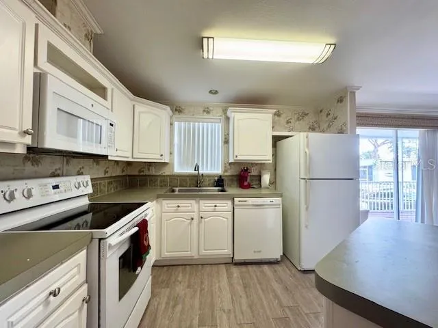 a kitchen with a refrigerator a sink and white cabinets
