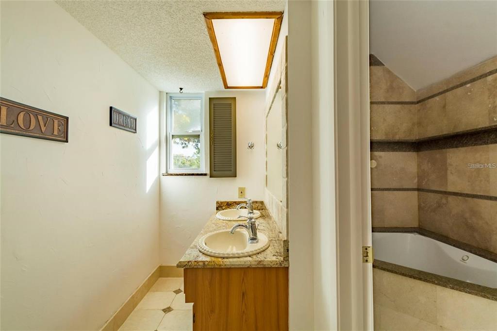 1647 Hobbit Road Dunedin, FL 34698 - Photo 13 of 36 a bathroom with a sink a mirror and a shower
