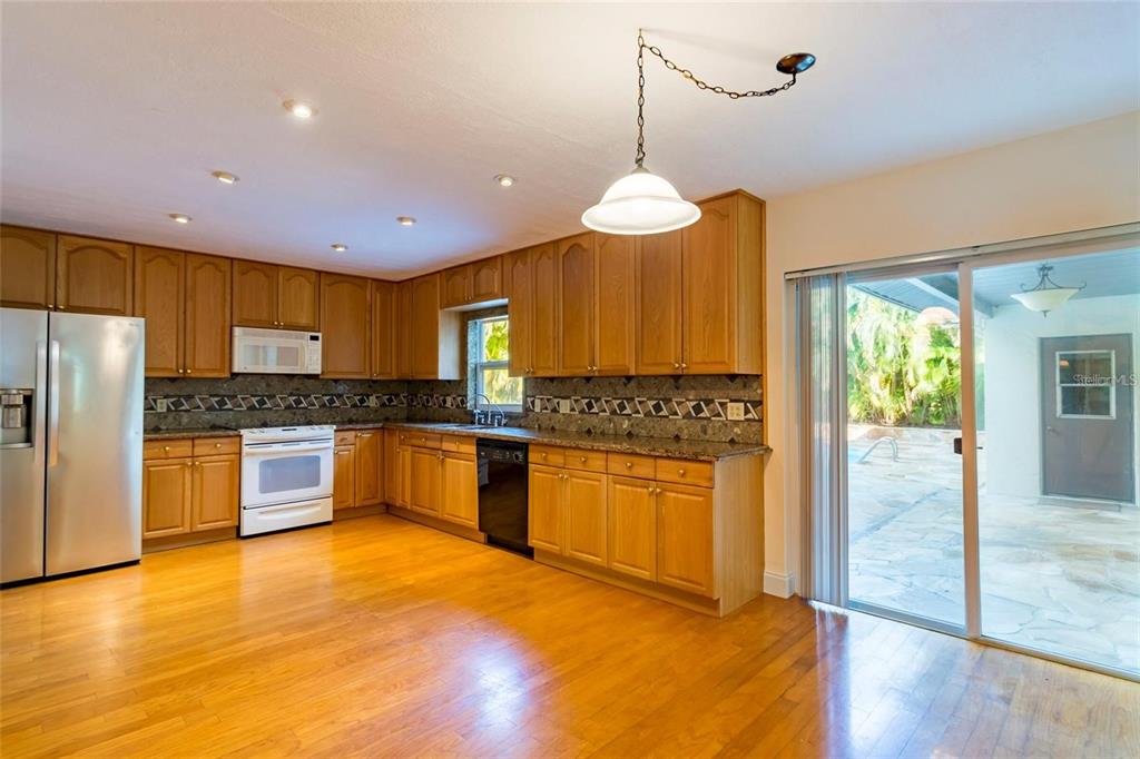 1647 Hobbit Road Dunedin, FL 34698 - Photo 25 of 36 a large kitchen with granite countertop a large counter top stainless steel appliances and wooden floor