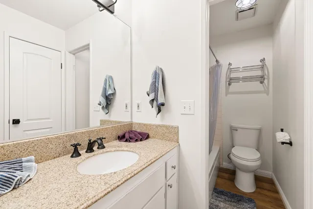 a bathroom with a granite countertop sink mirror vanity and toilet