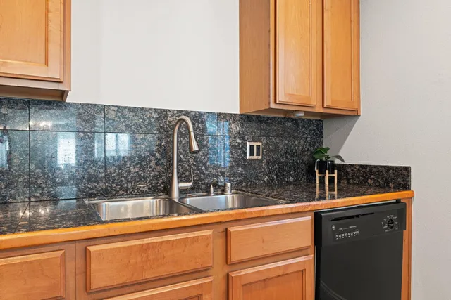 a kitchen with granite countertop a sink and a white cabinets