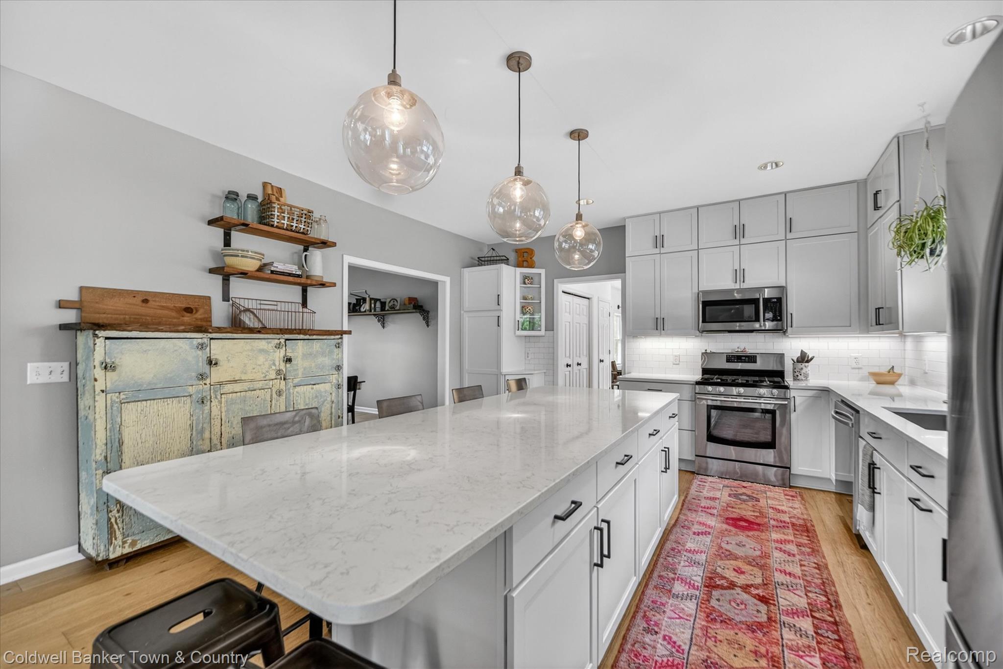 918 Gray Fox Court Howell, MI 48843 - Photo 11 of 84 Spacious kitchen featuring an expansive central island with a light-toned countertop, pendant lighting, stainless steel appliances, and light wood-finish flooring