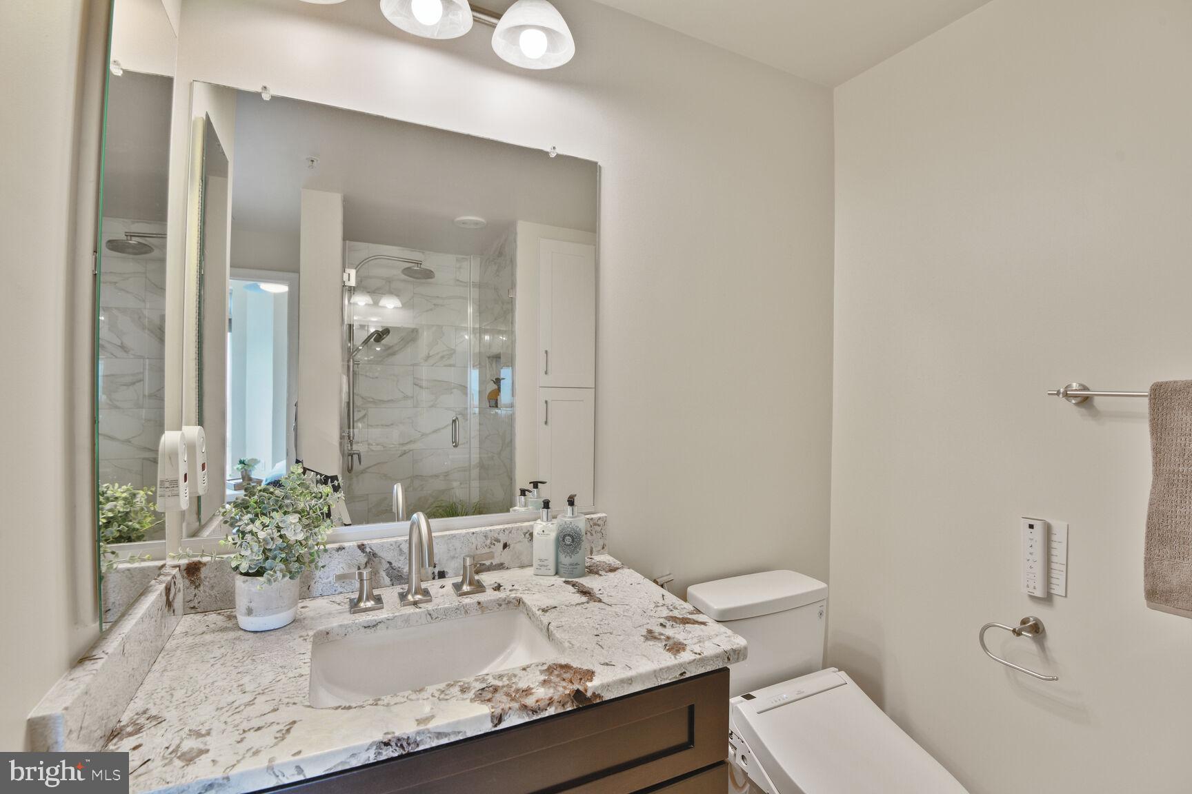 930 Wayne Avenue, Unit 1403 Silver Spring, MD 20910 - Photo 21 of 37 a bathroom with a granite countertop sink a toilet and a mirror