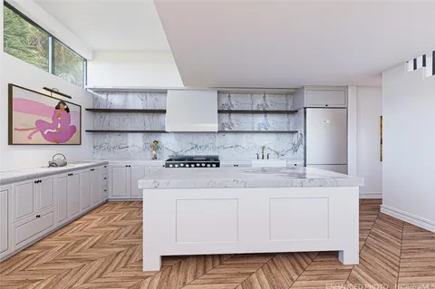 a room with a sink a stove and white cabinets