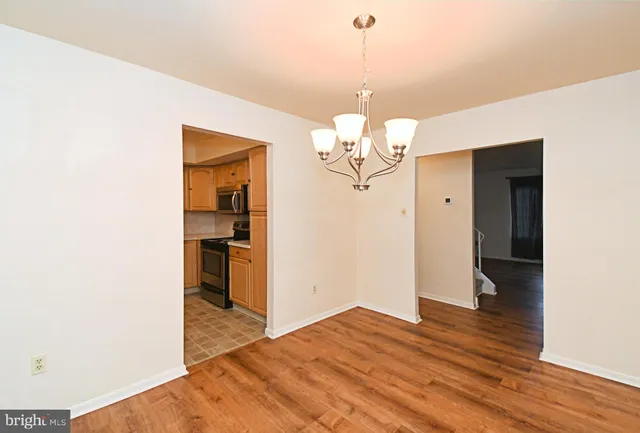 a view of a room with wooden floor kitchen and chandelier