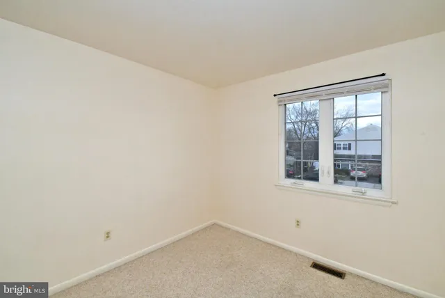 a view of front of a house with a large tree and wooden fence