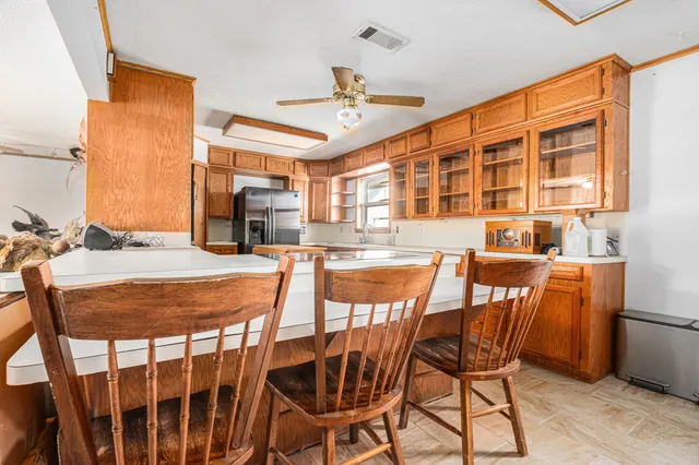 a dining room with stainless steel appliances kitchen island granite countertop a dining table and chairs with wooden floor