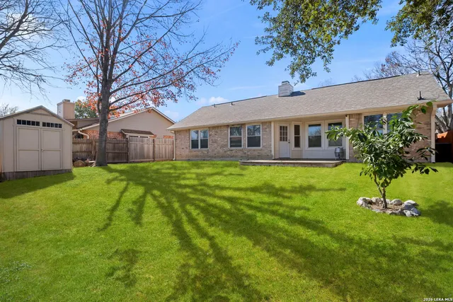 a view of a house with a big yard potted plants and large tree