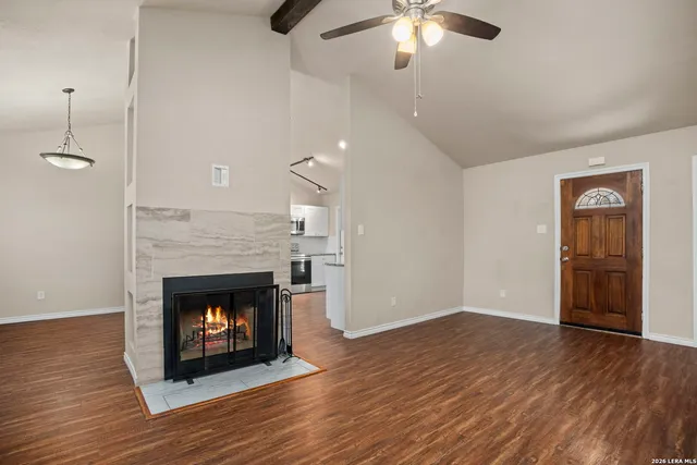 a view of an empty room with wooden floor fireplace and a window