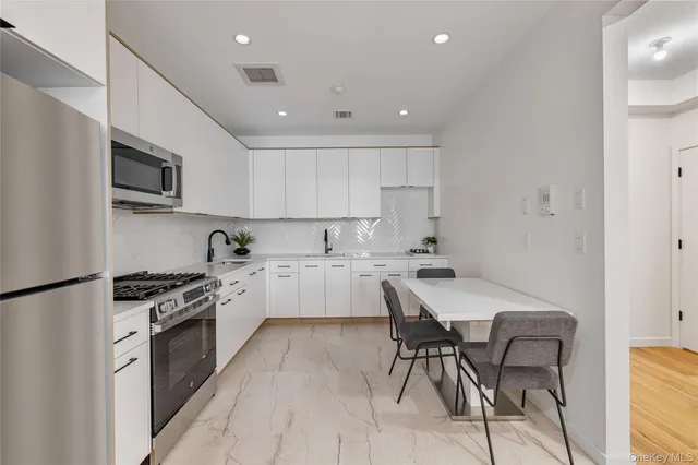 a kitchen with granite countertop white cabinets and stainless steel appliances