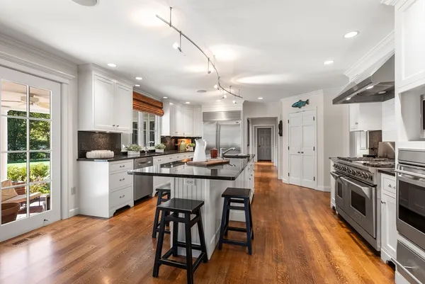 a kitchen with stainless steel appliances a dining table chairs stove and refrigerator