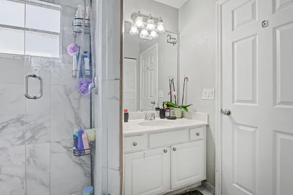 a bathroom with a sink vanity granite tub shower and mirror