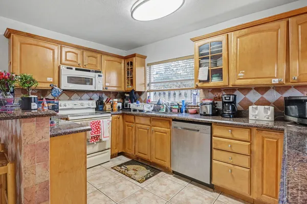 a kitchen with stainless steel appliances granite countertop a stove a sink and a microwave