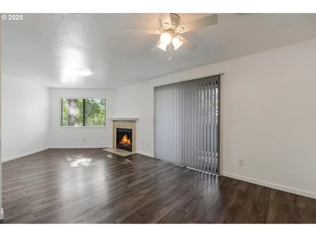 an empty room with wooden floor chandelier fan and windows