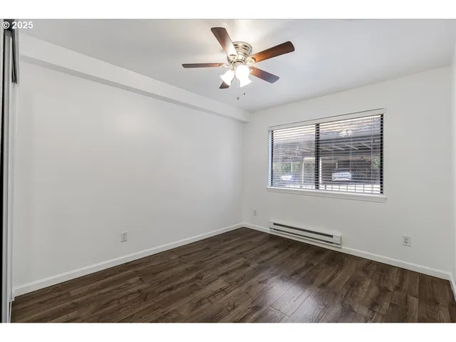 an empty room with wooden floor chandelier and windows