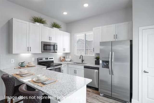 a kitchen with stainless steel appliances granite countertop a refrigerator a stove a sink a dining table and chairs