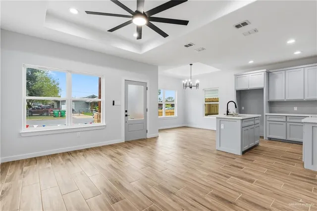 a view of an empty room and kitchen with wooden floor and window