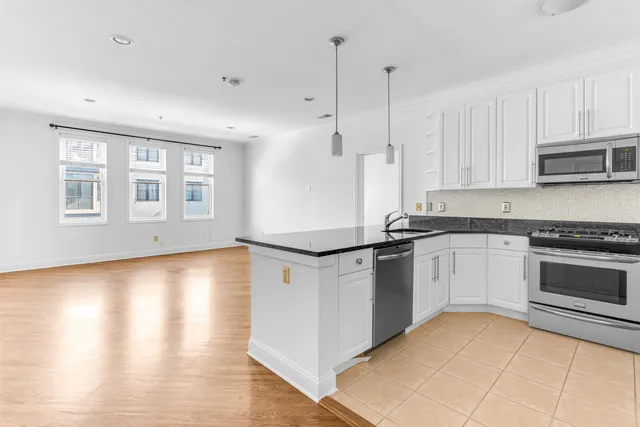 a kitchen with stainless steel appliances granite countertop a stove a sink and white cabinets