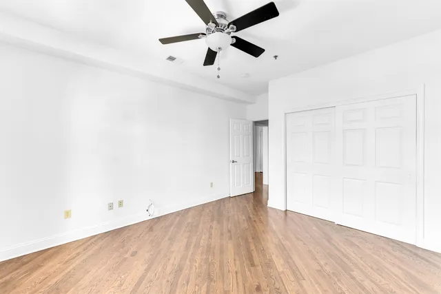 an empty room with wooden floor and a ceiling fan