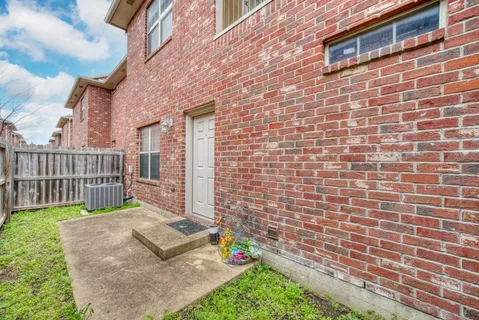 a brick house with a small yard and wooden fence