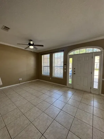 a view of an empty room with window and chandelier fan