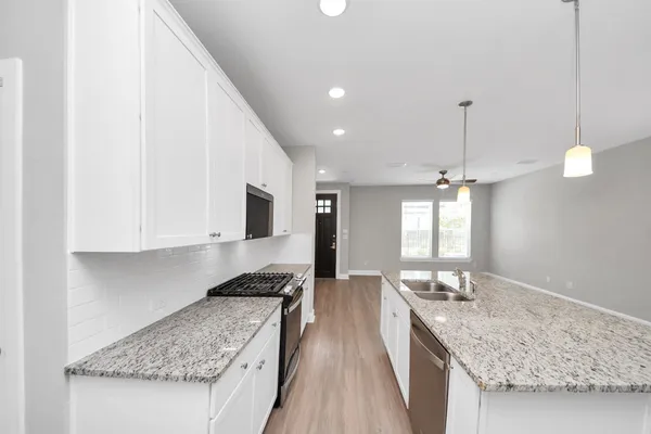 a kitchen with kitchen island granite countertop a refrigerator a sink a stove a microwave and wooden cabinets