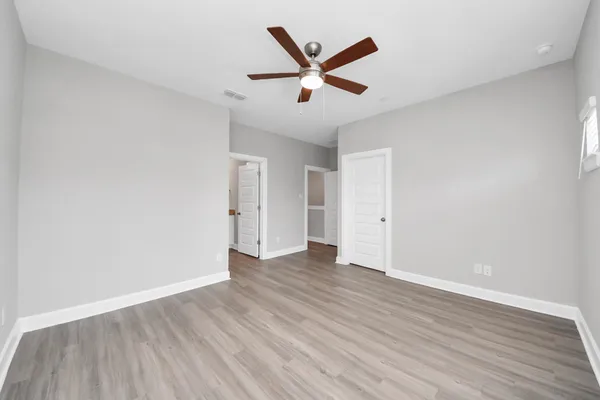 an empty room with wooden floor and a ceiling fan