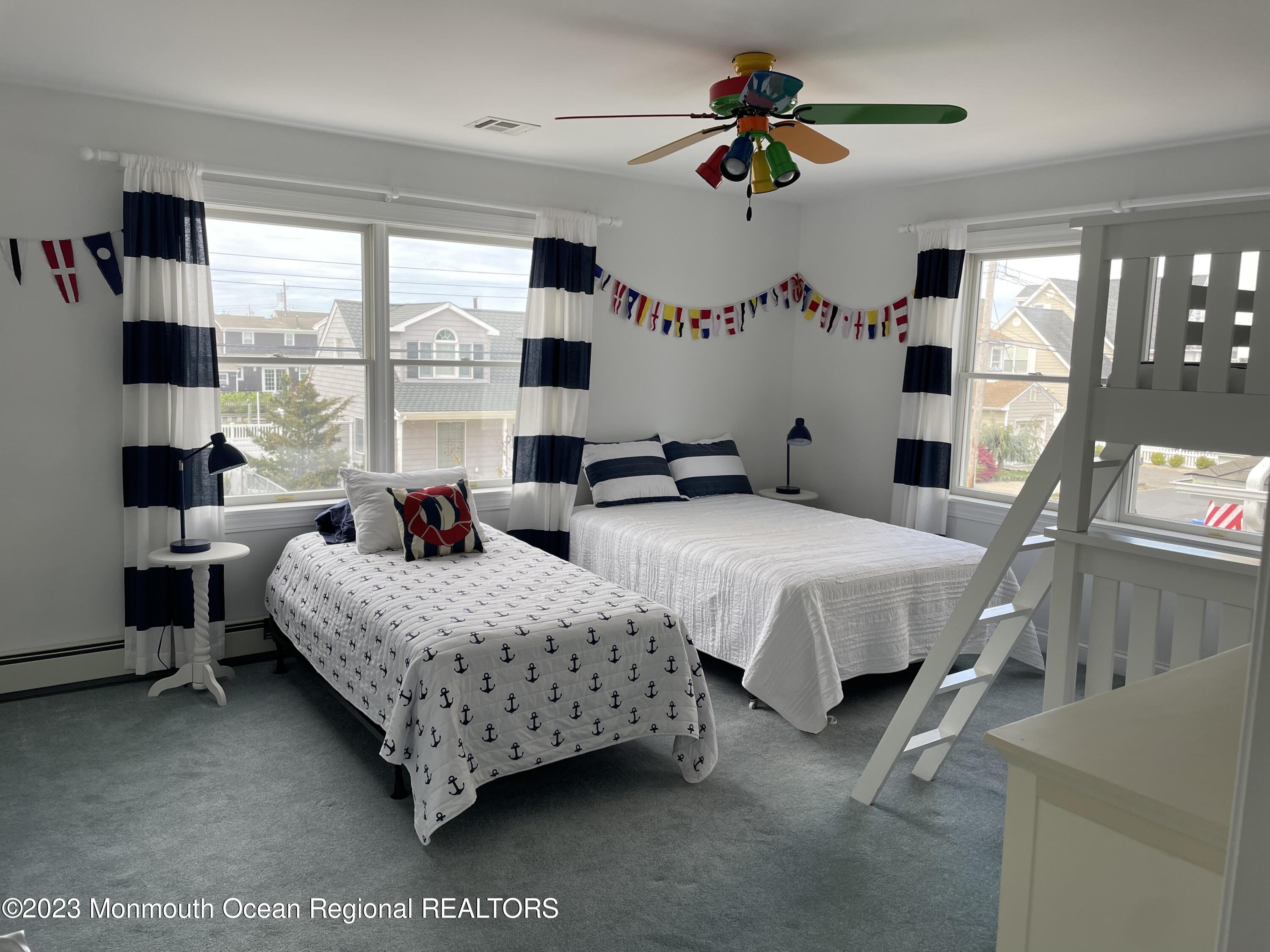 304 Cutter Lane Mantoloking, NJ 08738 - Photo 30 of 54 a spacious bedroom with two beds and a chandelier