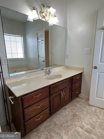 a bathroom with a granite countertop sink a light fixture and a mirror
