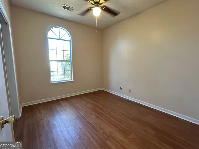 an empty room with wooden floor chandelier and windows