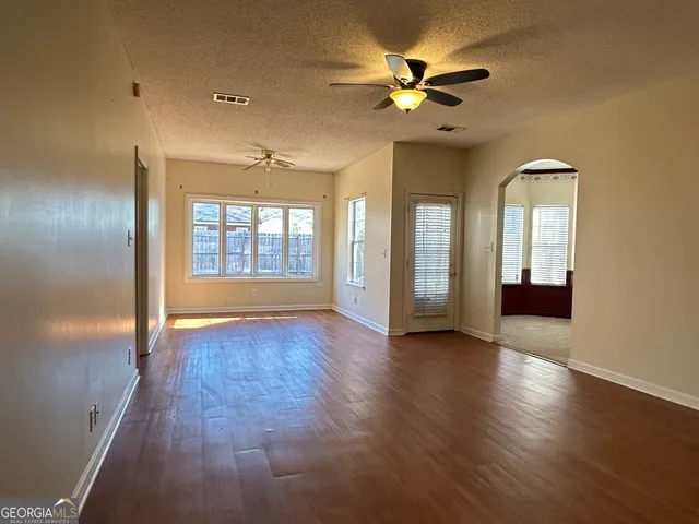 a view of an empty room with a window and wooden floor