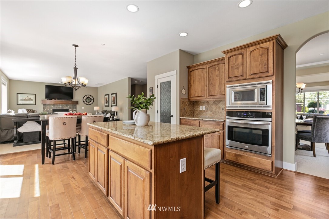 21703 31st Drive Southeast Bothell, WA 98021 - Photo 12 of 34 a kitchen with stainless steel appliances kitchen island granite countertop a stove a sink dishwasher and a dining table with wooden floor