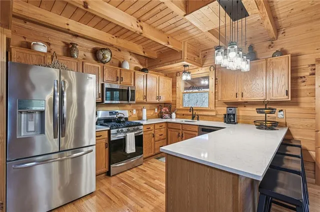 a kitchen with stainless steel appliances granite countertop a refrigerator a sink dishwasher a stove and a refrigerator with wooden floor