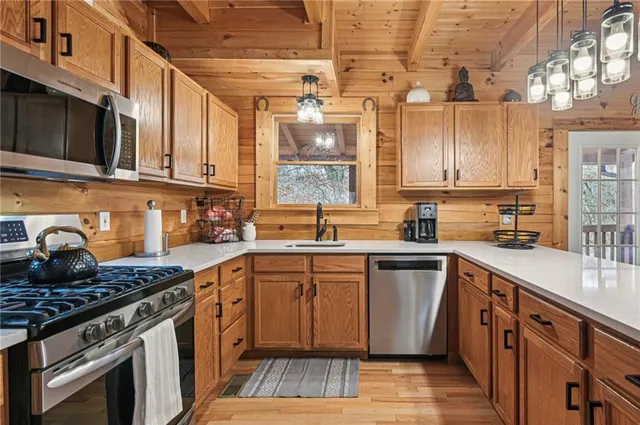 a kitchen with stainless steel appliances granite countertop a stove a sink dishwasher and a microwave oven with large cabinets