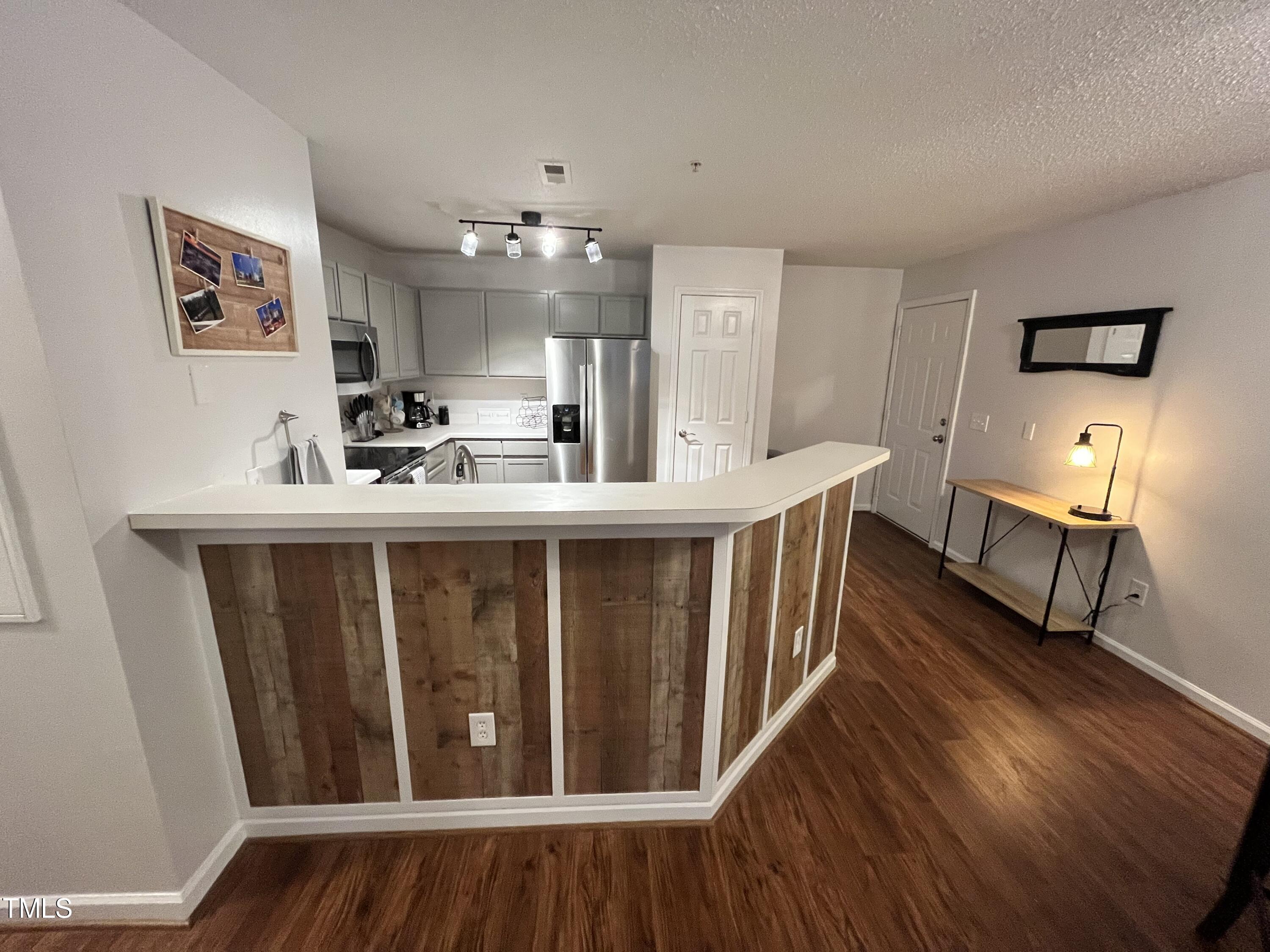 a room with stainless steel appliances a kitchen island hardwood floor and a living room