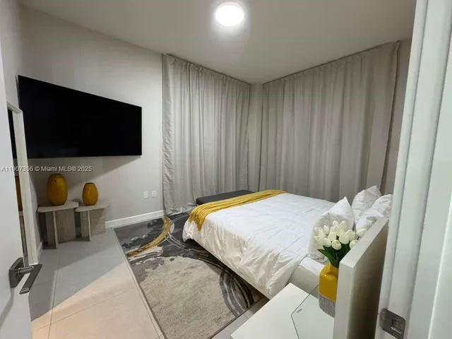 a bedroom with a bed a flat screen tv and dresser