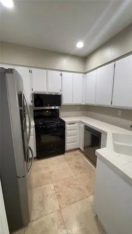 a kitchen with granite countertop a refrigerator and a stove top oven